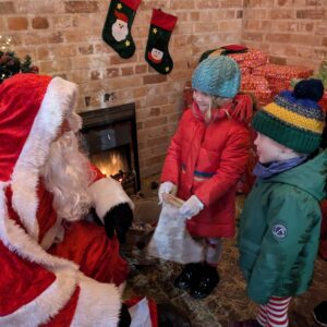 Santa with two smiling children all dressed up for winter