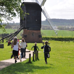 children running on field towards a windmill