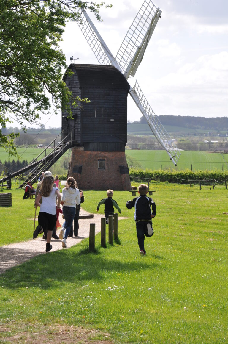 children running on field towards a windmill