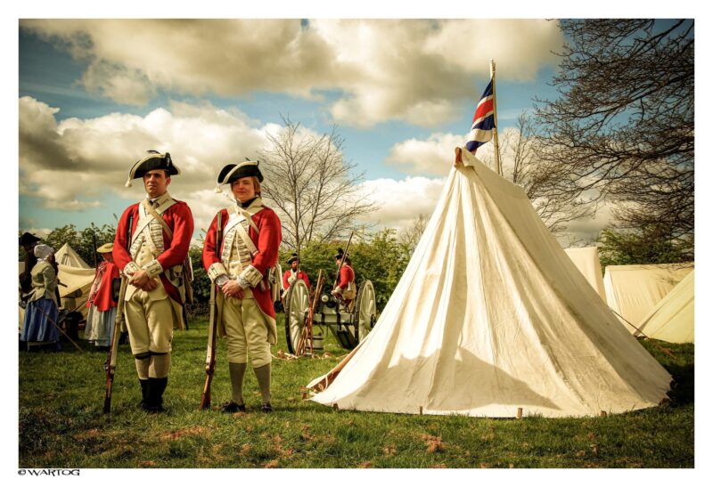 red coat soldiers standing next to historical tent