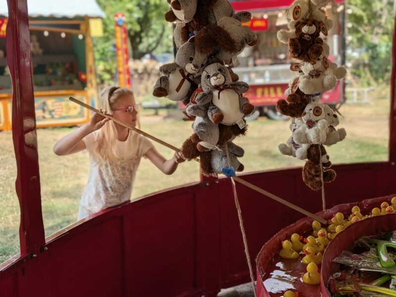 child hooking a duck on the fairground side stall